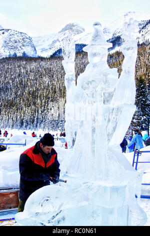 Il Lago Louise, CANADA - Jan 22, 2011: Un ghiaccio scultore scolpisce un alto blocco di ghiaccio con un utensile di potenza durante il ghiaccio annuale Magic Festival tenutosi in Cana Foto Stock