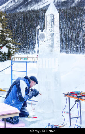 Il Lago Louise, CANADA - Jan 22, 2011: Un ghiaccio scultore scolpisce un alto blocco di ghiaccio con un utensile di potenza durante il ghiaccio annuale Magic Festival tenutosi in Cana Foto Stock