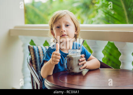 Un ragazzo beve un drink da un carruba. Foto Stock