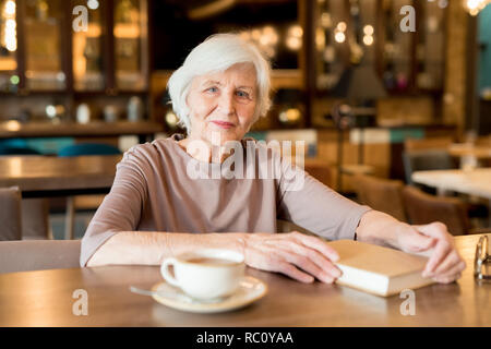 Grey-haired lady senior rilassante in cafe Foto Stock