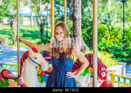 Donna godendo nel parco di divertimenti e di equitazione sulla giostra colorata casa Foto Stock