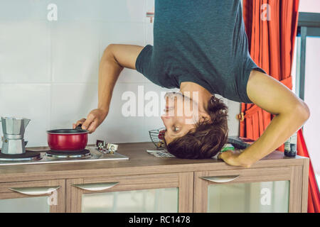 Un uomo si erge sulle sue mani capovolto in cucina Foto Stock