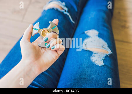 Ragazza adolescente in holey jeans tiene in mano e gioca con un dispositivo a rotazione vorticosa Foto Stock