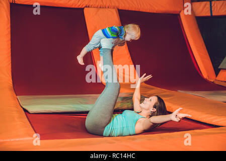 Madre e figlio saltando su un trampolino nel parco fitness e facendo exersice in ambienti interni Foto Stock