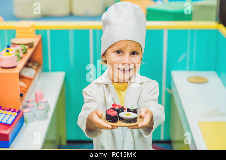 Il ragazzo gioca il gioco come se fosse un cuoco o un baker in bambini cucina Foto Stock