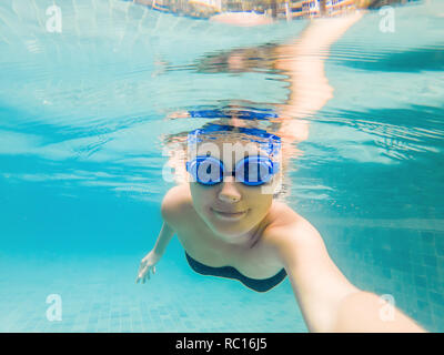 Una donna con immersioni occhiali è di nuoto in piscina sotto l'acqua