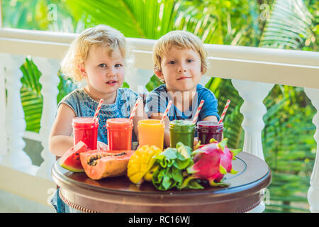 Bambini bere colorati Frullati salutari.. Anguria, papaia, mango, spinaci e dragon frutta. I frullati, succhi di frutta, bevande, bevande con varietà di frutta fresca su una tavola di legno Foto Stock