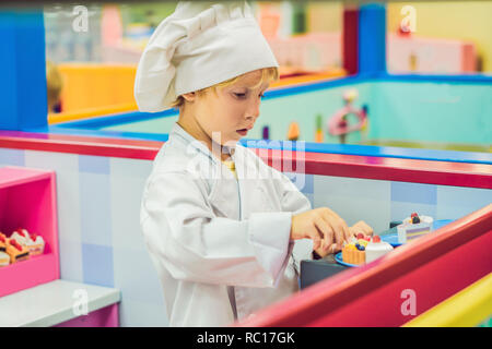 Il ragazzo gioca il gioco come se fosse un cuoco o un baker in bambini cucina Foto Stock