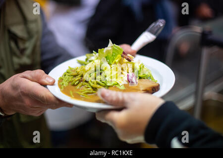 Stuttgart, Germania. Xiii gen, 2019. Un uomo prende un piatto di cibo durante il primo giorno dei Vespri. Per la venticinquesima volta la più antica chiesa Vesper in Germania fornisce persone bisognose con pasti caldi e più per sette settimane. Credito: Sebastian Gollnow/dpa/Alamy Live News Foto Stock