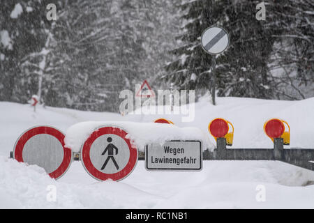 Rottach Egern, Germania. Xiii gen, 2019. Indicazioni su una strada chiusa indicare il pericolo di valanghe. Dopo l intensa nevicata dei giorni scorsi, disgelo con la pioggia ha impostato in molti luoghi, aumentando il carico di neve sui tetti. Credito: Lino Mirgeler/dpa/Alamy Live News Foto Stock