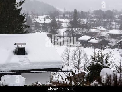 Rottach Egern, Germania. Xiii gen, 2019. Vista la coperta di neve tetti di Rottach-Egern. Dopo l intensa nevicata dei giorni scorsi, disgelo con la pioggia ha impostato in molti luoghi, aumentando il carico di neve sui tetti. Credito: Lino Mirgeler/dpa/Alamy Live News Foto Stock