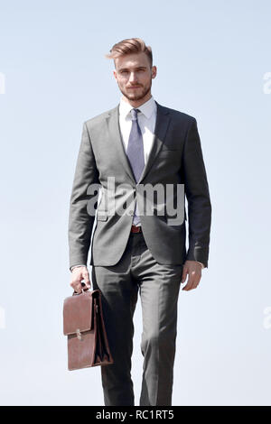 Fiducioso imprenditore con valigetta in pelle in avanti passo-passo Foto Stock