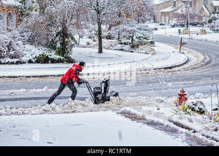 A est di Hannover, NJ / Nov 2014 - Uomo utilizza lo spalaneve per cancellare il suo marciapiede anteriore Foto Stock