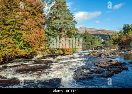 Più piccole cascate alle cascate di Dochart sul fiume Dochart a Killin in Scozia con il fiume Dochart ponte su una soleggiata giornata autunnale Foto Stock