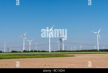 Linee di alimentazione aeree e le moderne turbine eoliche nei campi in Germania Foto Stock