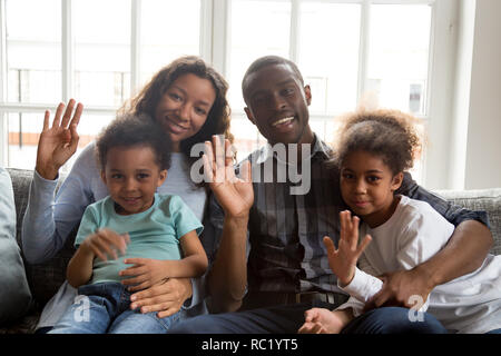 Felice famiglia africana con i bambini a sventolare le mani guardando la fotocamera Foto Stock