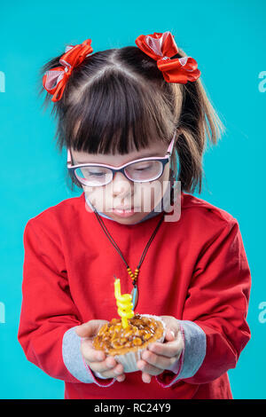 Bambina in tutto vestito di rosso in piedi contro la parete blu Foto Stock