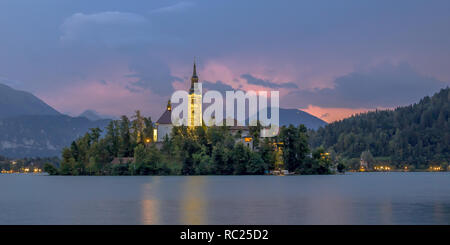 Il lago di Bled con la chiesa di Santa Maria e le montagne del fondale sotto il cielo tempestoso, Slovenia, Europa Foto Stock