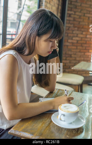 Giovane donna rispondendo alle chiamate telefoniche Foto Stock