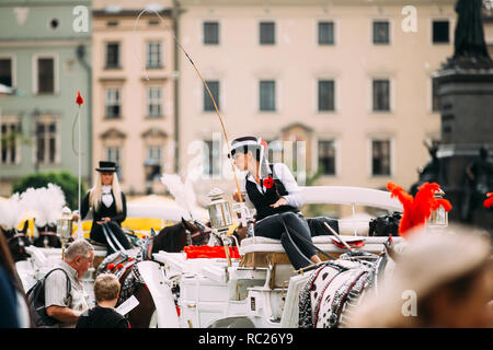 Cracovia in Polonia - Agosto 28, 2018: giovane bella donna che lavorano cocchiere sul vecchio stile carrozza pullman alla piazza principale del mercato nella soleggiata giornata estiva. Foto Stock