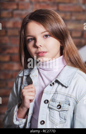 Ritratto poco fashion kid. Per i bambini il concetto di moda. Tanga eleganti bambina guarda fiducioso, ribelle. Bella faccia bambino caucasico indossando giacca denim,jeans. Foto Stock