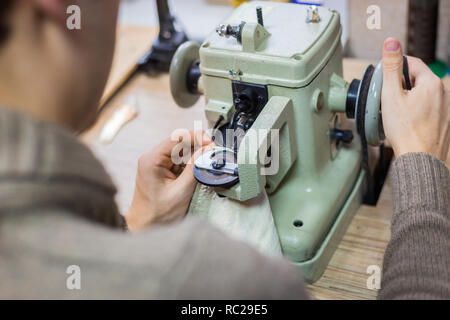 Maschio professionale skinner, pellicciaio utilizzando una speciale macchina cucitrice per la cucitura della pelle pelliccia all'atelier, workshop. Moda e marocchineria concept Foto Stock