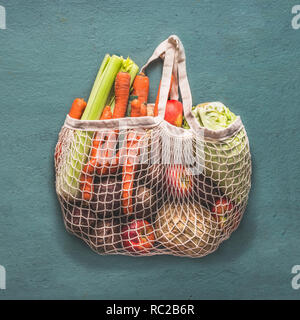 Riutilizzabili stringa netto shopping bag piena di varie azienda agricola biologica di verdure dal mercato locale su sfondo rustico, vista dall'alto . Pulite e il cibo sano co Foto Stock