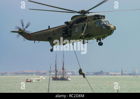 La British Royal Navy Commando Sea King elicottero con Royal Marines fast roping giù per una barca in ostaggio la pratica di salvataggio dello scenario di funzionamento Foto Stock