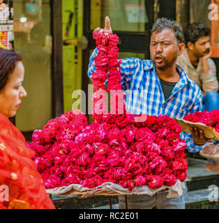 Vrindavan, India / Febbraio 22, 2018 - Uomo vende red flower leis dalla sua tabella di strada Foto Stock