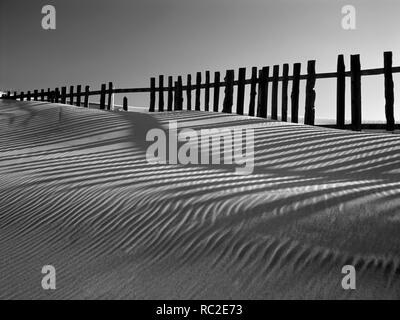 Mare duna di sabbia contro il profondo blu del cielo con recinti di legno e belle ombre (fotografia analogica. 120 film). Foto Stock