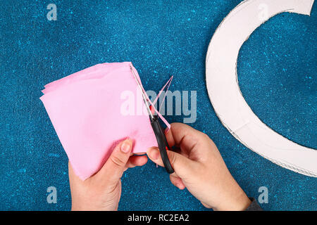 A forma di cuore decorata ghirlanda di fiori artificiali realizzati di tessuto rosa di tovaglioli di carta. Idee regalo per il giorno di San Valentino, arredamento per amore giorno, concetto Febbraio 14 Foto Stock