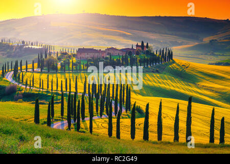 Famosa meta turistica e luogo di fotografia. Maestoso tramonto colorato e il settore agricolo con la tipica pietra toscana case sulla collina vicino a Siena Foto Stock