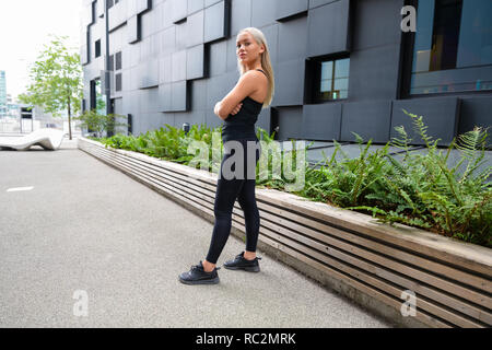 Fiducioso femmina guida urbana in piedi con le braccia incrociate Foto Stock