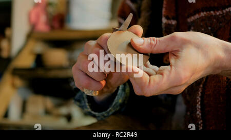 Professional potter maschio lavora in officina, studio - rendendo il tappo per il bollitore. Immagine ravvicinata di potter con le mani in mano. Fatti a mano, small business, creazione di concetto di lavoro Foto Stock