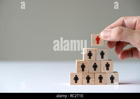 Mettendo mano cubo di legno blocco sulla piramide superiore per il concetto di leadership Foto Stock