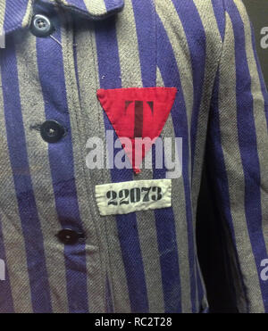 Un triangolo rosso su striped uniforme utilizzato in campi di concentramento nazisti durante la Seconda Guerra Mondiale sul display alla fiera "tocchi di statualità' a Praga, Repubblica Ceca. Il badge è contrassegnato con la lettera "T" significato i nemici politici di nazionalità ceca, dalla parola tedesca "Tschechien' per il ceco. La mostra dedicata al centenario della Cecoslovacchia corre fino al 31 ottobre 2018. Foto Stock