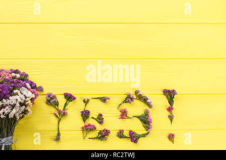 Parola sì fatta di fiori e bouquet in legno di colore giallo. Vista dall'alto. Copyspace, spazio libero per il testo. Foto Stock