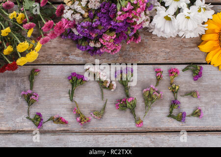 Romantico luminosa parola amore da fiori su legno. Vista superiore, piatto laici. Foto Stock