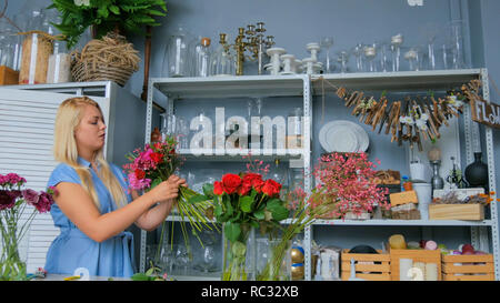 Professional donna artista floreale, fioraio in vestito blu rendendo bellissimo mazzo di nozze in officina, negozio di fiori. Fiorai, fatta a mano e small business concept Foto Stock