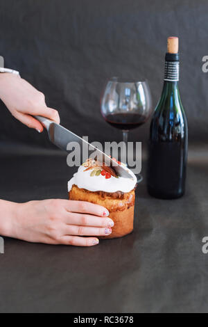 Tagliare la torta di Pasqua in mano womans. La pasqua ortodossa tradizionale pane dolce, kulich. Vacanze di Pasqua a colazione. Taglio femminile torta di Pasqua Foto Stock