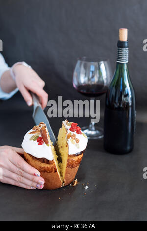 Tagliare la torta di Pasqua in mano womans. La pasqua ortodossa tradizionale pane dolce, kulich. Vacanze di Pasqua a colazione. Taglio femminile torta di Pasqua Foto Stock