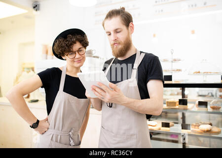 Contenuto personale giovane di coffee shop controllo dell'ordine su tablet Foto Stock