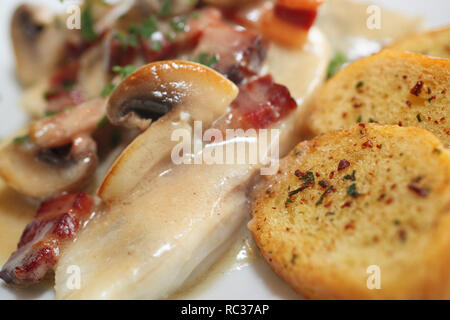 Il coregone con funghi e pancetta affumicata e stagionata baguette - cucina Burgundy-French, il fuoco selettivo, macro, dettaglio Foto Stock