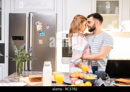 Giovane coppia amorevole abbraccio in cucina Foto Stock