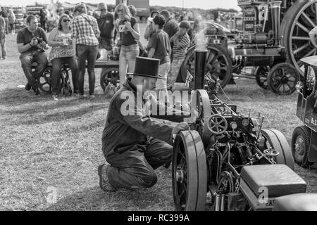 Uomo in ginocchio di fronte a aminiature motore trazione a vapore di Preston Rally, Kent, Inghilterra Foto Stock