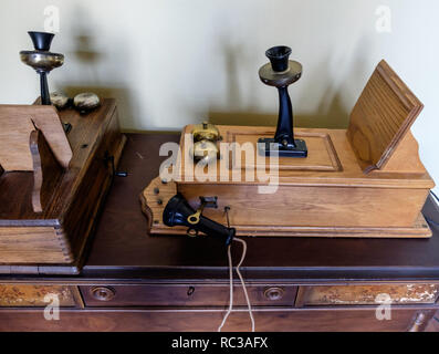 Antiche in legno picture frame parete anteriore telefoni, Cattedrale top back, appendere il ricevitore per pony, & inclinata piattaforma di scrittura, che giace piatto su un tavolo di legno. Foto Stock