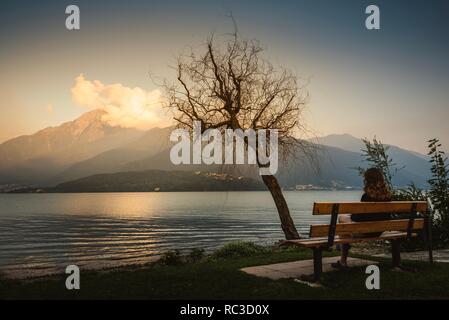 Donna guardando il tramonto sul Lago di Como, Italia Foto Stock