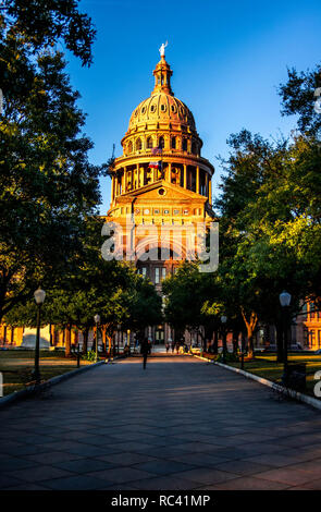 La gente che camminava sul percorso verso l'ingresso del Texas State Capital building al tramonto con il cielo azzurro e cupola sopra Foto Stock