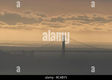 Il Golden Gate Bridge di San Francisco come si vede da lontano in Berkeley Hills durante un bel tramonto quando il cielo era di colore arancione. Foto Stock