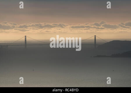 Il Golden Gate Bridge di San Francisco come si vede da lontano in Berkeley Hills durante un bel tramonto quando il cielo era di colore arancione. Foto Stock